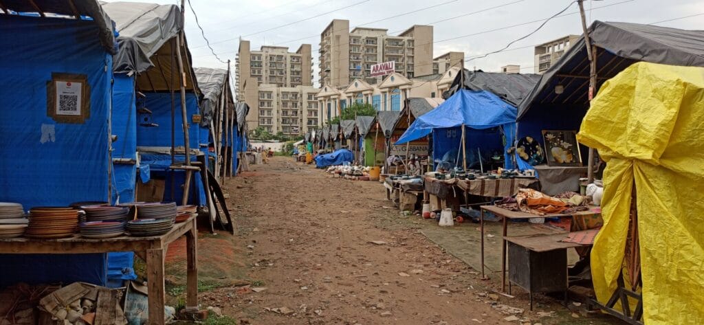 Makeshift tents serving as stalls at the Banjara Market. Highrises of Faridabad in the background.