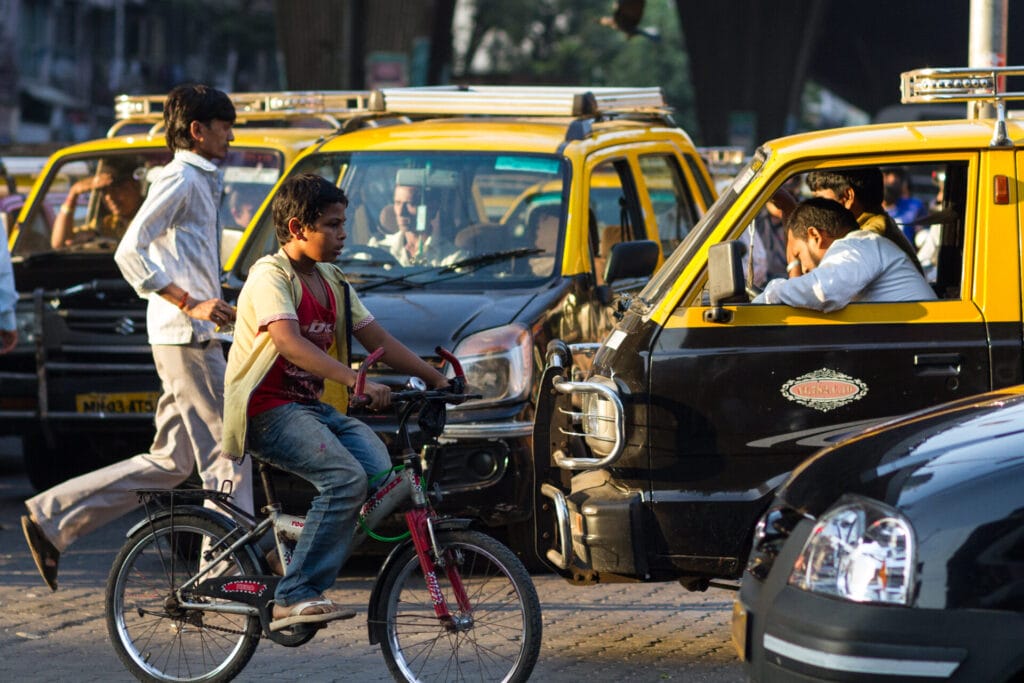 boy riding cycle in Mumbai traffic
